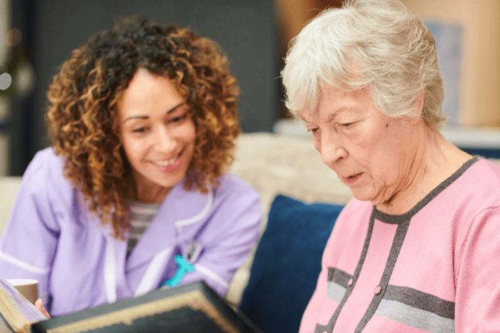 senior woman looking in a photo album with her nurse