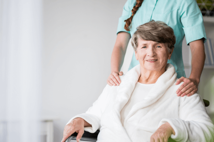 senior woman in a wheelchair carefully assisted by her nurse