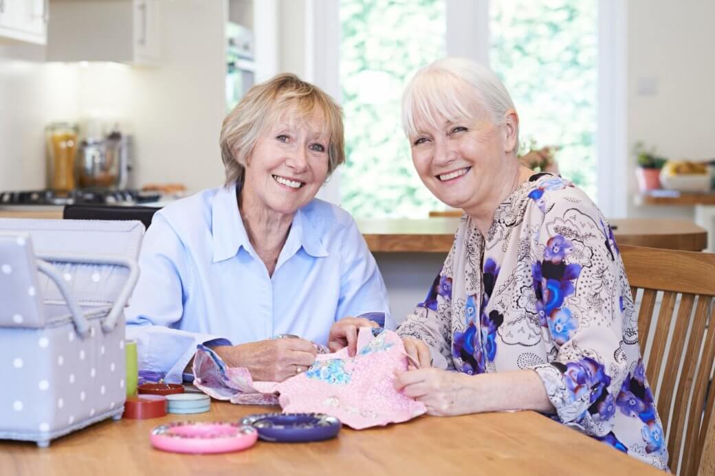two senior women happily quilting