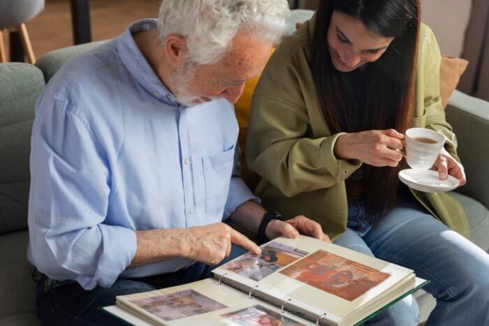 A senior man and woman engrossed in a photo book, reliving cherished moments. Transition Anxiety may be present.