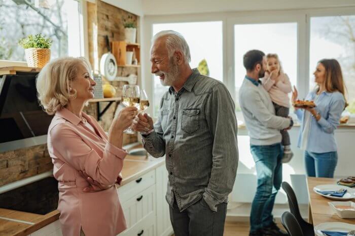 An older couple toasting in a kitchen with their family. New Residents: Celebrating love and new beginnings with their loved ones.