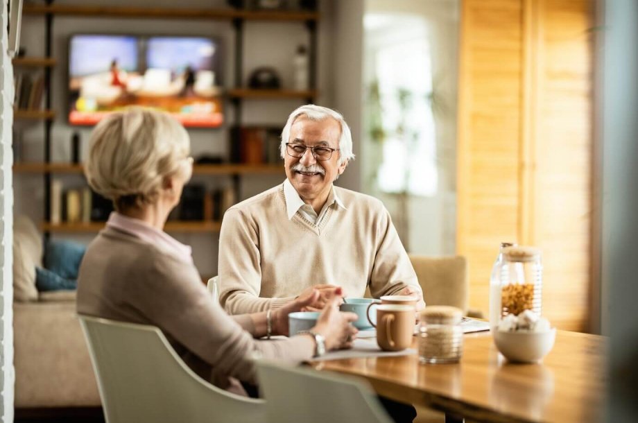 An older couple enjoying a cozy moment at a table in their living room, cherishing their personal privacy.