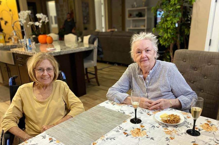 Two seniors sitting at a table with food.