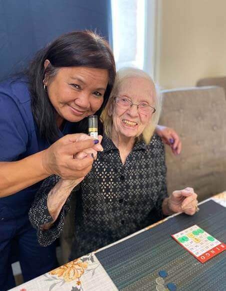 A senior and a skilled nurse playing bingo.