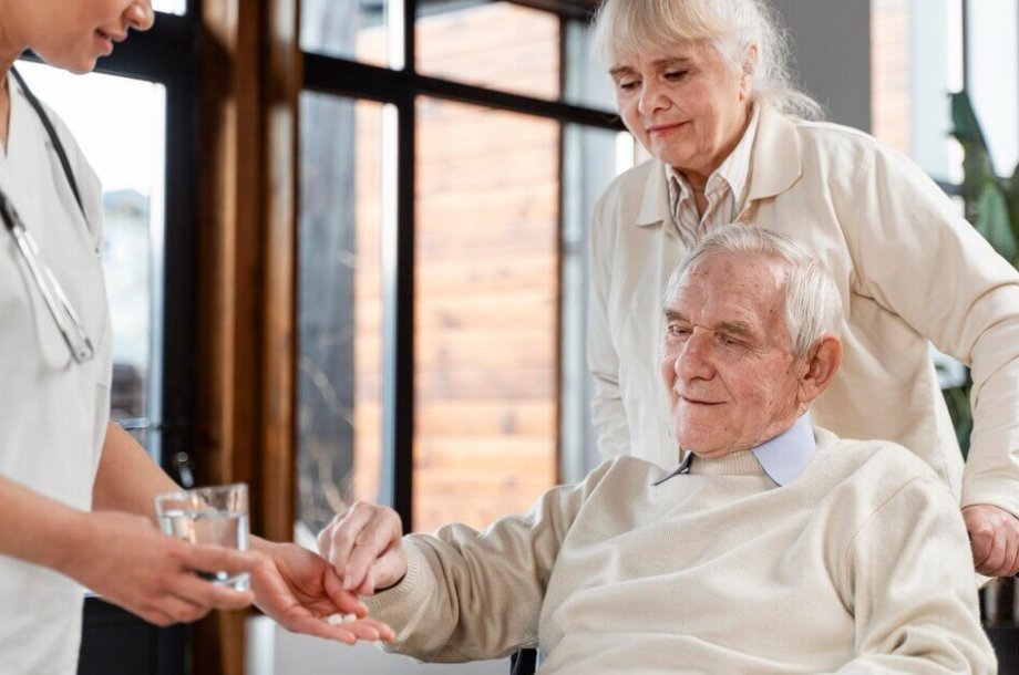 Caregiver assisting senior in his medication in senior living assisted living