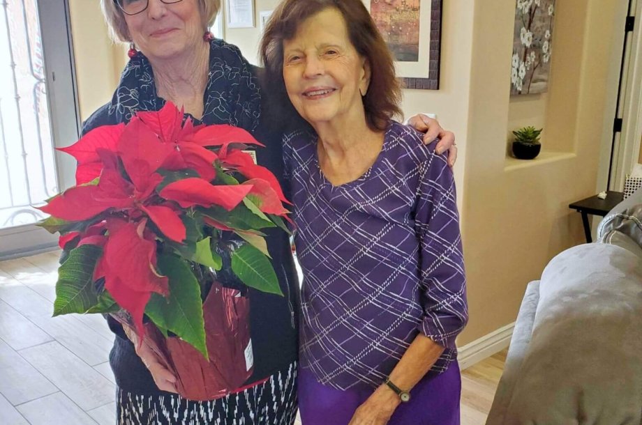 a senior visited by her daughter with a poinsettia plant